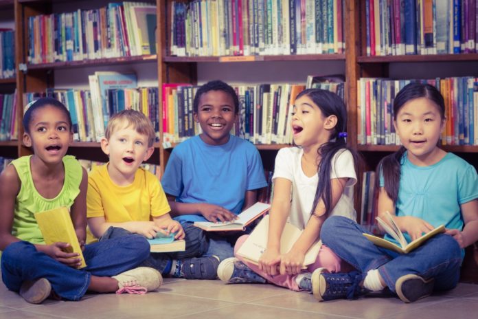 Pupils sitting on the ground and reading books in the library