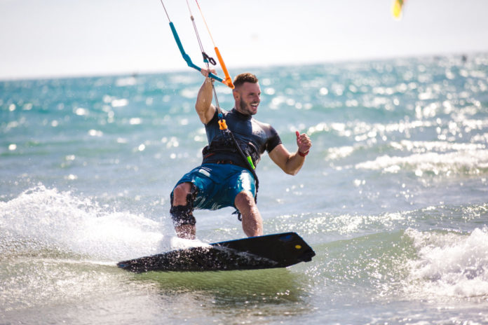 Kitesurfing. Man rides on kite on waves