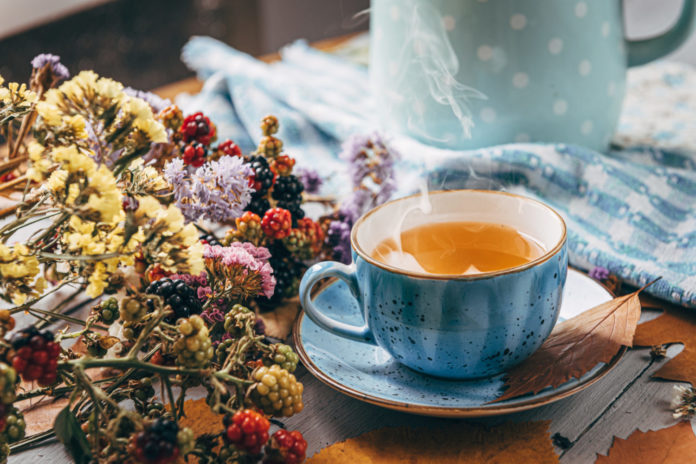 autumn warming tea on a wooden table with autumn tree leaves lyi