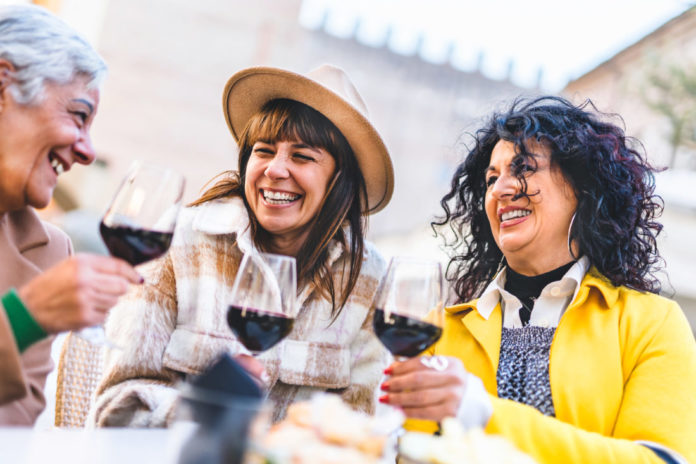 Happy women drinking and toasting red wine outdoors at bar restaurant-Mature senior people having fun together at bistrò pub-Group of female friends hanging out on city-Life style and laughing concept