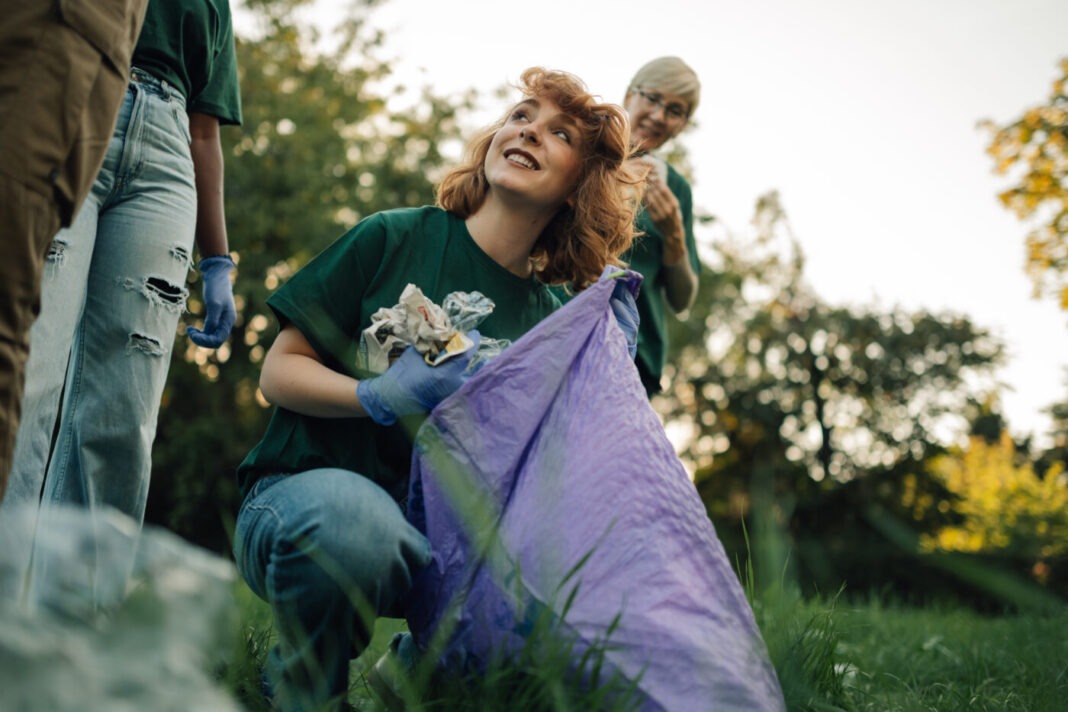 Young volunteer picking up trash in park with team